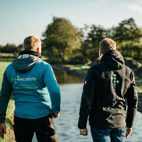 Zwei Mitarbeiter von ecodots stehen mit dem Rücken zum Betrachter und schauen auf das Wasser.